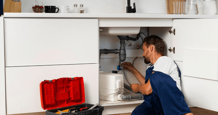 A local specialist clearing a blocked pipes under a kitchen sink in a Camden home.