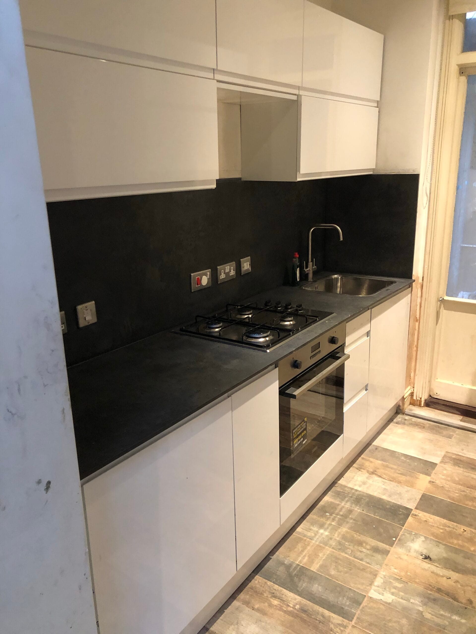 Kitchen sink with black worktop after unblocking